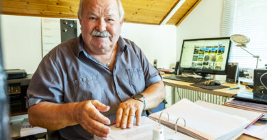 An seinem Schreibtisch und in seinem Element: Heinz Willi Poensgen blättert in einem Ordner mit Unterlagen über Kommern. Im Hintergrund ist eine seiner Facebook-Gruppen auf dem Bildschirm zu sehen. Foto: Ronald Larmann/pp/Agentur ProfiPress
