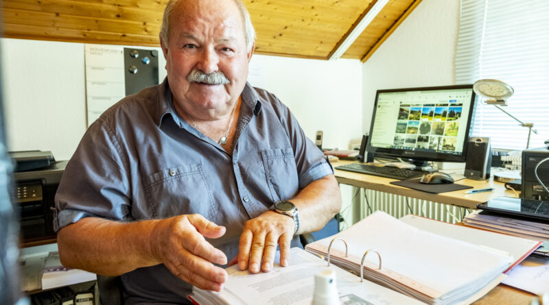 An seinem Schreibtisch und in seinem Element: Heinz Willi Poensgen blättert in einem Ordner mit Unterlagen über Kommern. Im Hintergrund ist eine seiner Facebook-Gruppen auf dem Bildschirm zu sehen. Foto: Ronald Larmann/pp/Agentur ProfiPress