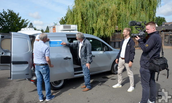 Nüßmann und Buhs brachten gleich die Aufkleber der „Fernsehlotterie“ am neuen Wagen an, die Detering und Kalbe im Gepäck hatten. Foto: Henri Grüger/pp/Agentur ProfiPress