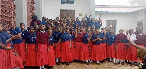 Winkende Schülerinnen der bischöflichen Schule St. Agnes in Mahenge mit Besuchern aus dem Mechernicher Mutterhaus der Communio in Christo im Hintergrund. Foto: Charles Libuhela/CIC/pp/Agentur ProfiPress