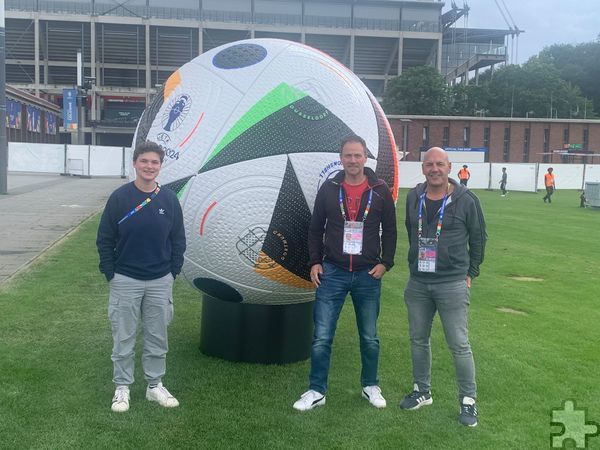 Vor dem Einsatz mussten die Volunteers zum Training, zur Registrierung und zum Einkleiden: Zur Erinnerung hat das Team Eifel mit Laurie Simon (v.l.), Roland Huppertz und Jörg Piana ein Foto vor dem EM-Ball gemacht. Foto: Huppertz/pp/Agentur ProfiPress