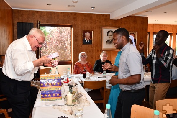 Father Peter Omenyi aus Nigeria, dahinter Seminarist Simon Peter Aliu aus Uganda, beide Studenten in Rom, übergeben die Geschenke der Afrikaner in der Communio in Christo an Spiritual Rudolf Ammann, im Hintergrund (v.r.) Communio-Schwester Dorothea und Hedwig Wipperfürth. Foto: Manfred Lang/pp/Agentur ProfiPress