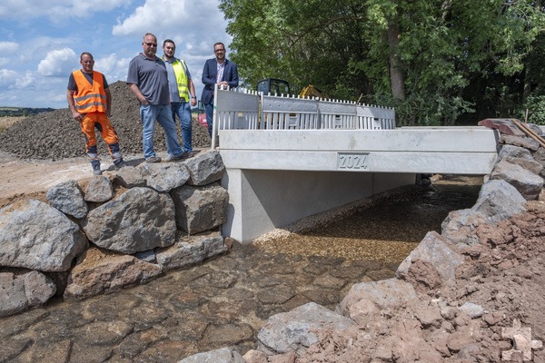 Die neue Brücke bei Floisdorf: Der Erste Beigeordnete Thomas Hambach (v.r.), Tiefbausachbearbeiter Marvin Perschke und Teamleiter Andreas König machten sich mit Polier Jens Plinius ein Bild von den Arbeiten. Foto: Ronald Larmann/pp/Agentur ProfiPress