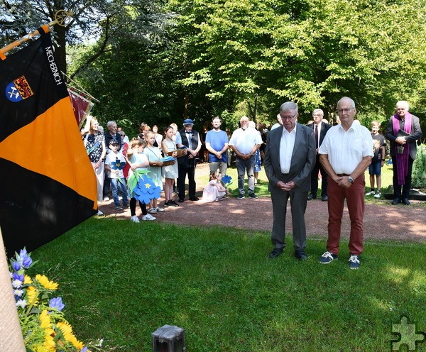 Bürgermeister Dr. Hans-Peter Schick (r.) und Ortsbürgermeister Günther Schulz haben einen Kranz für die Verstorbenen aus Mechernich niedergelegt, im Hintergrund links Kinder, die Papierblumen für die Gräber gebastelt hatten, rechts Pfarrer Erik Pühringer, in der Mitte hinten und links hinten die Vize-Bürgermeister Günter Kornell und Heinrich Schmitz. Foto: Manfred Lang/pp/Agentur ProfiPress