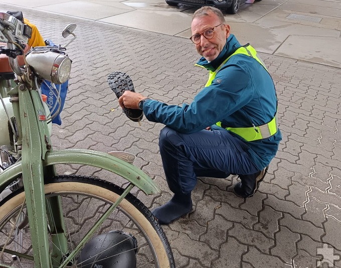 Volker Zart sorgt unter dem Vordach einer Tankstelle in Witten erst einmal für halbwegs trockene Füße, indem er das Spritzwasser ausschüttet. Foto: Ingo Hochgürtel/pp/Agentur ProfiPress