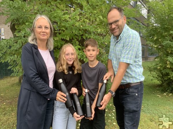 Marion Berend, Vorsitzende des Fördervereins der Schule, präsentiert mit Lehrer Andreas Maikranz und zwei Fünftklässlern die nachhaltig produzierten Trinkflaschen des Mechernicher Gymnasiums Am Turmhof. Foto: Bernhard Karst/pp/Agentur ProfiPress