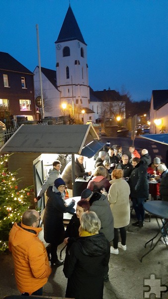 Im Schatten der Pfarrkirche sorgen Glühwein- und erstmals ein Reibekuchen-Stand für Weihnachtsmarkt-Stimmung. Die Hilfsgruppe Eifel ist mit einem Waffelstand dabei. Foto: Reiner Züll/pp/Agentur ProfiPress