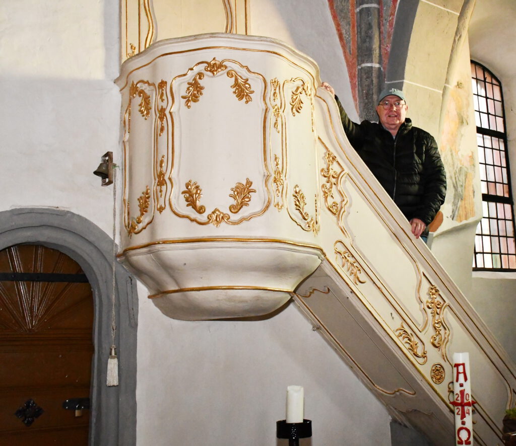 Der Predigtstuhl in der alten Kirche von Mechernich hatte einst seinen Platz in der Schlosskapelle des Hauses Rath zwischen Strempt und Roggendorf. Auf der Treppe ist der frühere Geschäftsführer des Kirchengemeindeverbandes Mechernich, Bertram Jannes, zu sehen, der den Mechernicher „Bürgerbrief“ auf eine interessante Kirchengeschichte aufmerksam machte. Foto: Sabine Roggendorf/pp/Agentur ProfiPress