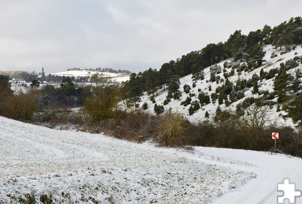 Kiefern, Wacholder, Schnee und das Dörfchen Harzheim mit der Pfarrkirche St. Goar im Hintergrund: Blick auf Halbmagerrasen und Kalkkuppe Halsberg zwischen Gilsdorf und Harzheim kurz nach Neujahr 2025. Foto: Sabine Roggendorf/pp/Agentur ProfiPress