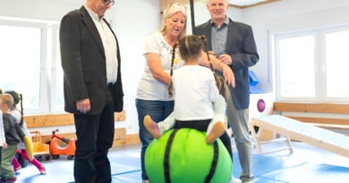 Kinder fliegen durch die Luft angeschubst von Kita-Leiterin Beate Hausmann-Solh. Ralf Claßen (r.) und Dr. Michael Stöhr freuen sich, dass mit der Spende der Mechernich-Stiftung der Schaukelball angeschafft wurde. Foto: Larmann/pp/Agentur ProfiPress