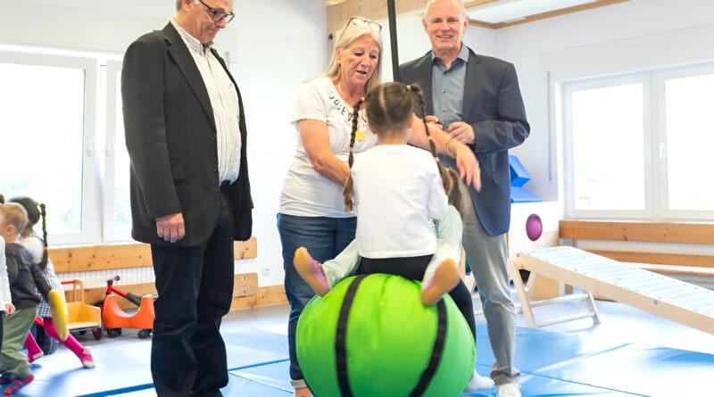 Kinder fliegen durch die Luft angeschubst von Kita-Leiterin Beate Hausmann-Solh. Ralf Claßen (r.) und Dr. Michael Stöhr freuen sich, dass mit der Spende der Mechernich-Stiftung der Schaukelball angeschafft wurde. Foto: Larmann/pp/Agentur ProfiPress