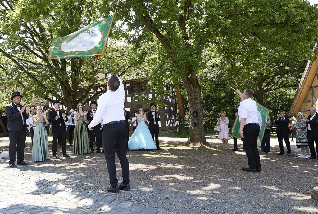 Vor dem Tante-Emma-Laden der Baugruppe Westerwald schwenkten die Ramersdorfer Fähnriche ihre Standarten zu Ehren des alten und des neuen Maikönigspaares. Foto: Stephan Everling/RRG/pp/Agentur ProfiPress