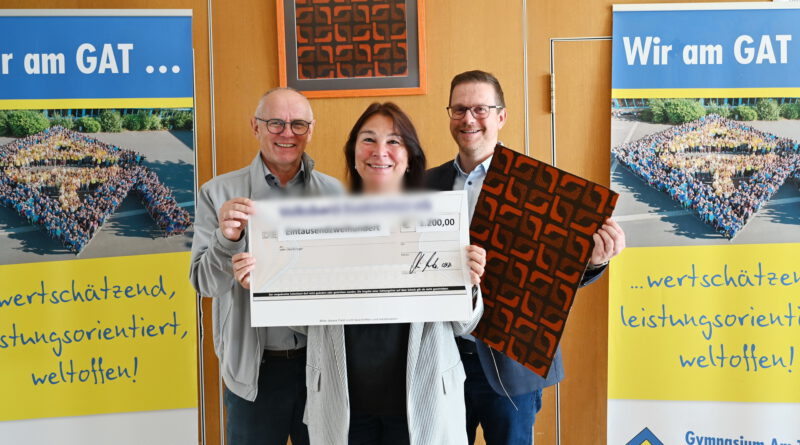 Karla Langer, Ralf Claßen (l.) und Micha Kreitz mit Teppichstücken aus der Aula und symbolischem Scheck bei der Spendenübergabe des Gymnasiums Am Turmhof an die Mechernich-Stiftung. Foto: Manfred Lang/pp/Agentur ProfiPress