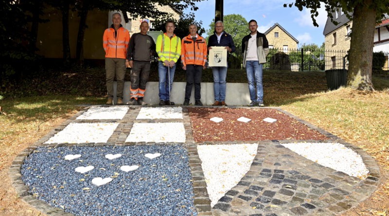 (V. l.) Marco Bohr und Detlef Abel („Universal-Bau GmbH“), Fachbereichsleiter Mario Dittmann und Rudi Mießeler von der MR- Ingenieurgesellschaft, Guido Fleischmann (Geschäftsführer „Universal-Bau GmbH“) und Ortsbürgermeister Björn Wassong vor dem neu angelegten Dorfwappen an der nagelneuen Ortsdurchfahrt. Foto: Henri Grüger/pp/Agentur ProfiPress