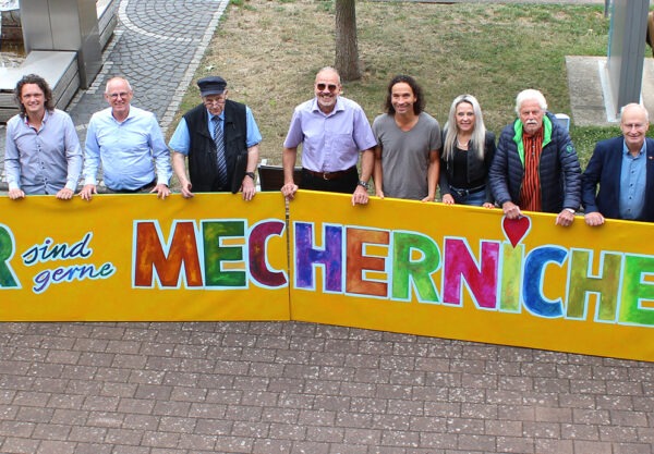 Viel Lust auf ein großes, fröhliches Stadtfest macht das knallbunte, vom Mechernicher Kurator Franz Kruse entworfene Kunstwerk, das die Musiker und Verantwortlichen nun vor dem Rathaus präsentierten. Foto: Kerstin Rottland/pp/Agentur ProfiPress