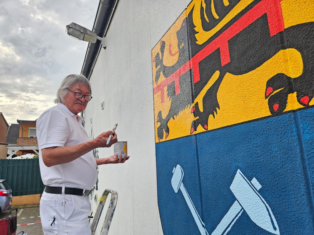 Auch der Mechernicher Kunstmaler Yklas Kosikejew malte auf der anderen Seite des ehemaligen Getränkemarktes begeistert mit. So zum Beispiel das Stadtwappen. Foto: Daniel Ottersbach/K.O.T./pp/Agentur ProfiPress