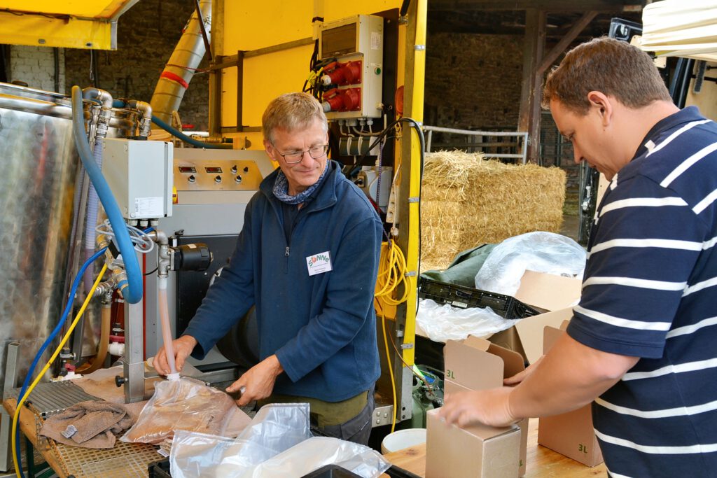 Den frisch gepressten Saft füllen Martin Holzportz (l.) und sein Team direkt für die Baumbesitzer in handliche Kartons ab. Foto: Cedric Arndt/RRG/pp/Agentur ProfiPress