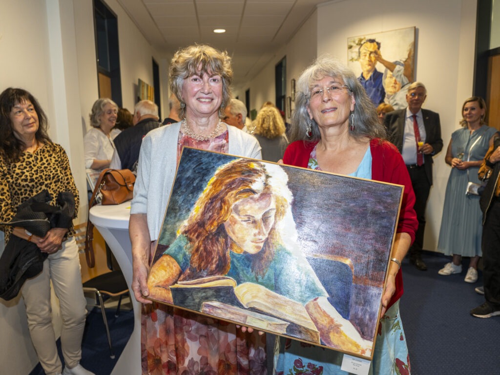 Nach zehn Jahren Malpause markierte das Bild die Leserin den künstlerischen Neuanfang von Yvonne Delisle (r.). Daran erinnerte ihre Freundin Petra Bergerhof während der Vernissage in der Galerie im Rathaus. Foto: Ronald Larmann/pp/Agentur ProfiPress