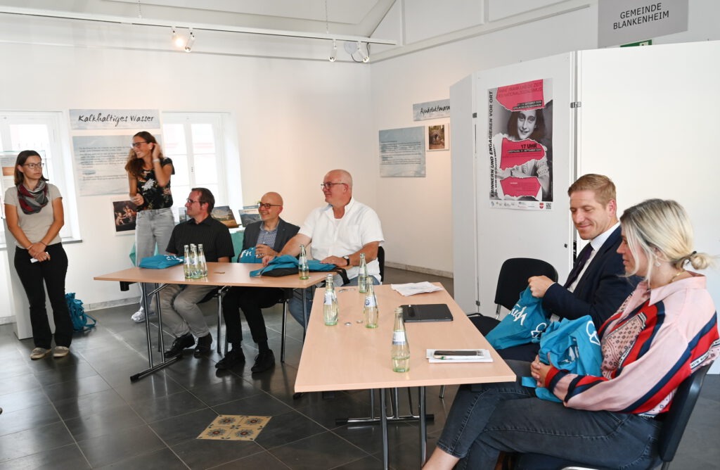 Auf dem Podium saßen (v.l.): Bürgermeisterin Jennifer Meuren, Landrat Markus Ramers, Historiker und Lehrer Markus M. Schmitz, Stefan Schmidt vom Volksbund Deutsche Kriegsgräberfürsorge und Olaf Ahrens von der Gesamtschule Eifel, links neben ihm Yvonne Fürsatz, Ortsvorsteherin und Mitglied des Heimatvereins Uedelhoven, und Kanstanze Bauer vom Volksbund. Foto: Manfred Lang/pp/Agentur ProfiPress
