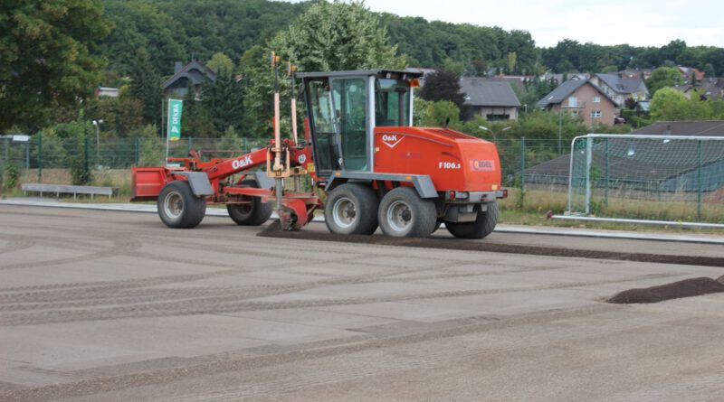 Mit dem Grader wird aktuell eine feine Lavaschicht eingeebnet. Auf sie kommt die elastische Tragschicht, die den Kunstrasen hält. Damit er nicht verrutscht, werden pro Quadratmeter 25 Kilogramm Sand verteilt. Foto: Kerstin Rottland/pp/Agentur ProfiPress