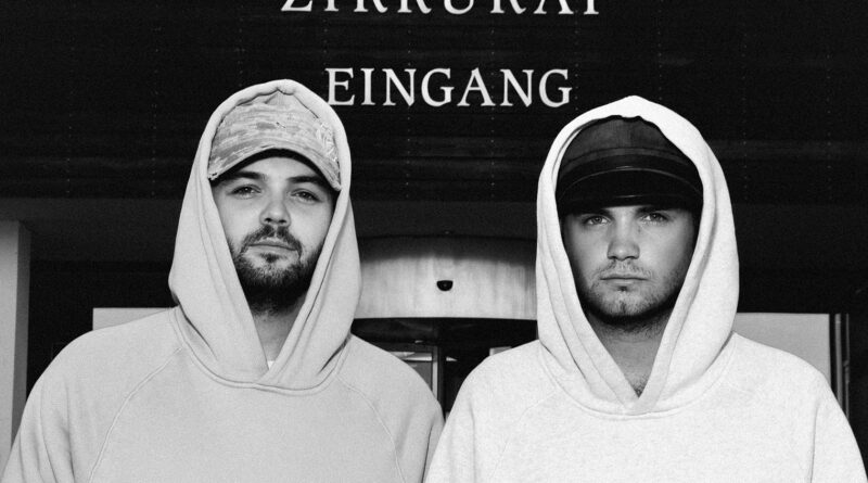 Mode, die international für Aufsehen sorgt, und in der ganz viel Mechernich steckt, macht Designer Luis Dobbelgarten (r.). Hier zeigt er mit seinem Bruder und Manager Leon Dobbelgarten den Hoodie mit Eifel-Therme-Zikkurat-Emblem. Foto: No/Faith Studios/pp/Agentur ProfiPress