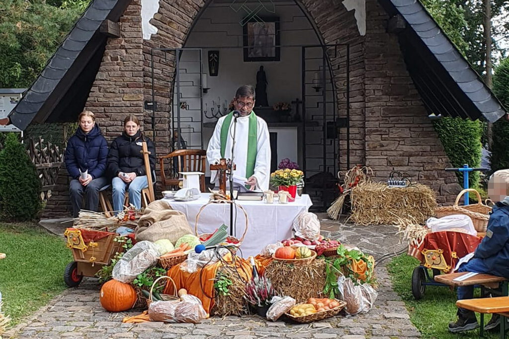 Pfarrer George Stephen Rayappan Packiam vor dem mit Erntegaben dekorierten provisorischen Altar vor der Mechernicher Barbarakapelle. Foto: Daniel Ottersbach/pp/Agentur ProfiPress