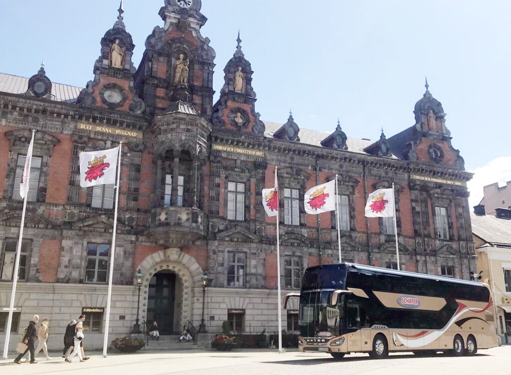 Moderner „Schäfer-Reisen“-Reisebus im Sommer 2025 vor einer beeindruckenden Fassade im schwedischen Malmö. Foto: Matthias Feuser/pp/Agentur ProfiPress