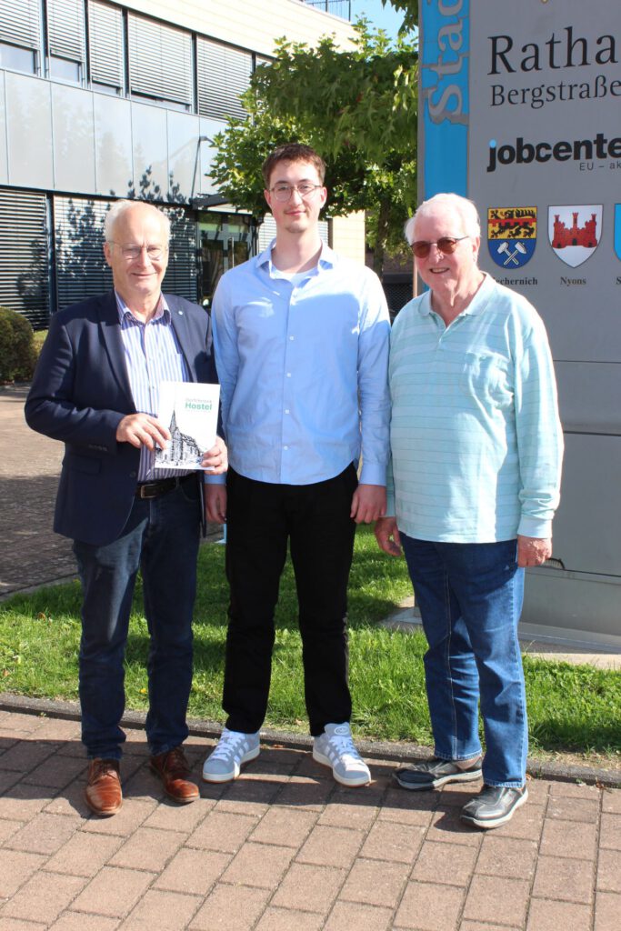 Das erste Exemplar für den ersten Bürger: Noch druckfrisch überreichte Autor Lucas Hamacher (Mitte) die nagelneue Dorfchronik zusammen mit Großvater Dieter Schröder (rechts) an Bürgermeister Hans-Peter Schick, der den 23-Jährigen zu den Recherchen über sein Heimatdorf Hostel ermutigt hatte. Foto: Kerstin Rottland/pp/Agentur ProfiPress