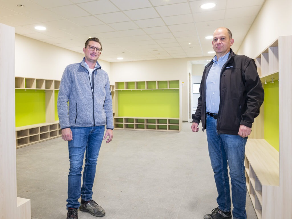 Der Garderobenraum, ausgestattet von der Firmenicher Tischlerei n.d.r, sieht doch schon gut aus: Die Projektverantwortlichen Christoph Breuer (l.) und Andreas Kurth sind zuversichtlich, dass die Grundschule nach den Herbstferien im neuen Gebäude starten kann. Foto: Ronald Larmann/pp/Agentur ProfiPress