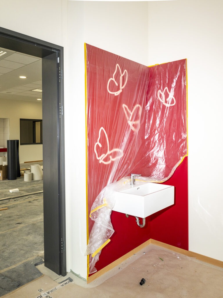 Das Waschbecken ist mit einer roten Wand und weißen Schmetterlingen hervorgehoben. Auch hier finden sich die Clusterfarben wieder. Foto: Ronald Larmann/pp/Agentur ProfiPress