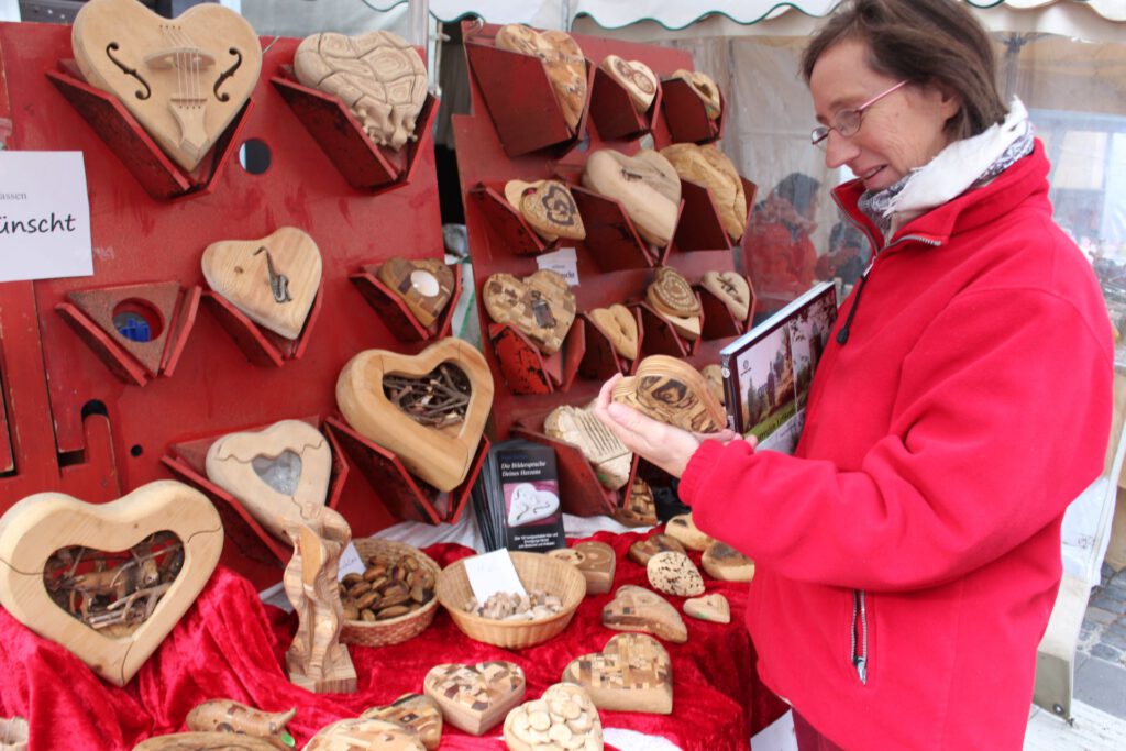 „Anfassen erwünscht!“, steht auf einem Zettel am Stand von Winni Eichen aus Bonn. Die Handschmeichler in Herzform sind aus den unterschiedlichen Hölzern wie Blauregen, Nussbaum, Buche und Wenge gefertigt. Foto: Kerstin Rottland/pp/Agentur ProfiPress