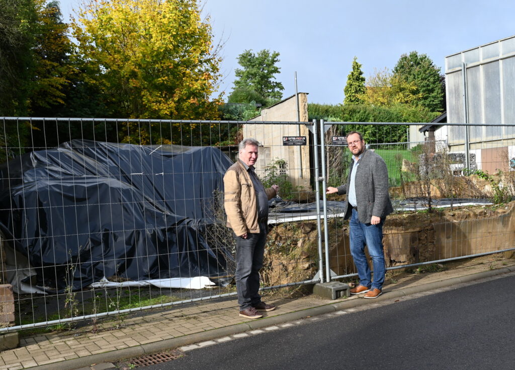 Ralf Gehlen (l.) und Thomas Hambach vor der mit schwarzer Folie abgedeckten Abrissimmobilie an der Weyerer Hauptstraße. Die Stadt ließ das einsturzgefährdete Gebäude auf Kosten des Eigentümers abtragen, um Passanten zu schützen. Foto: Manfred Lang/pp/Agentur ProfiPress