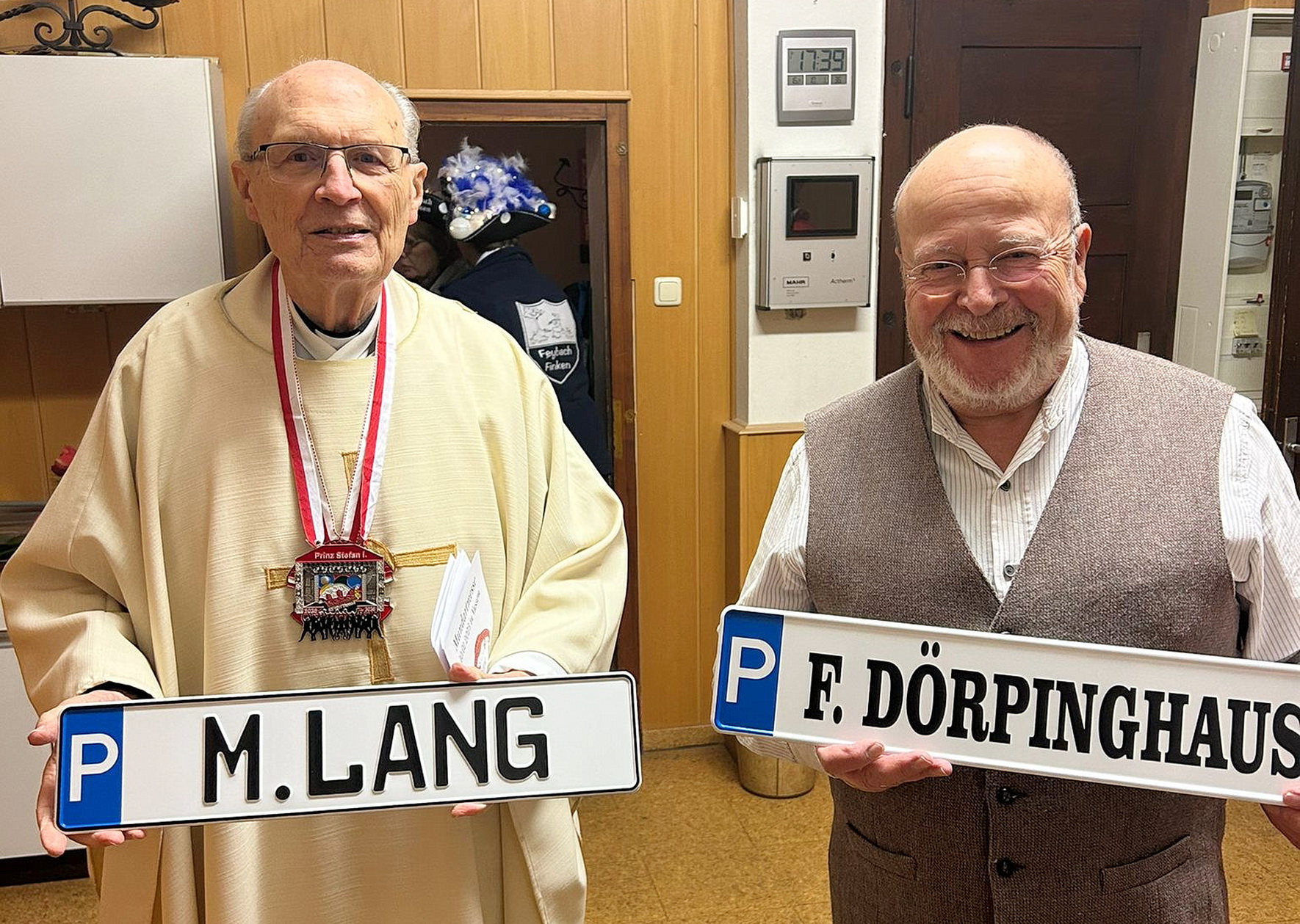 „Stets frei parken vor der Kirche“, versprachen die Vussemer Jecken Pfarrer Felix Dörpinghaus (l.) und Diakon Manfred Lang, die sich hier mit vertauschten Parkplatzschildern nach der Messe in der Sakristei dem Fotografen stellten. Foto: Marco Sistig/pp/Agentur ProfiPress