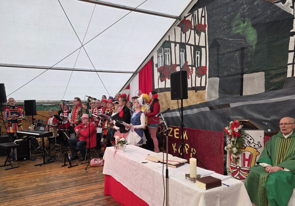 Platt, Huhdütsch unn op Englisch, aber immer mit „Schmackes“ unterhielt der Rhythmuschor „Kakus Vokale“ um Uli Schneider die Holzheimer Gottesdienstgemeinde. Im Vordergrund Pfarrer Felix Dörpinghaus, der Hauptzelebrant der Karnevalsmesse. Er lud die Gemeinde zu einem dreiminütigen Schweigen ein. Foto: Manfred Lang/pp/Agentur ProfiPress