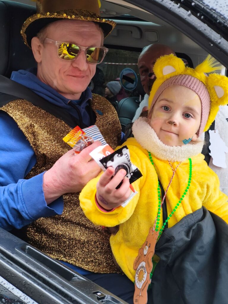 Auf Papas Schoß: Aus dem Begleitfahrzeug heraus reichte diese kleine Zugteilnehmerin den Jecken die Kamelle an. Foto: Kerstin Rottland/pp/Agentur ProfiPress