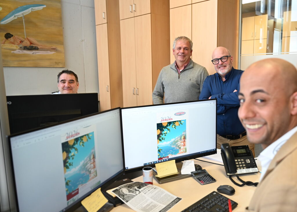 Reyad Khaled bei der Arbeit am neuen Busreisekatalog von „Schäfer-Reisen“, im Hintergrund (v.r.) Reiseverkehrskaufmann Matthias Feuser, Inhaber Christoph Lehner und Disponent Carsten Clemens. Foto: Manfred Lang/pp/Agentur ProfiPress