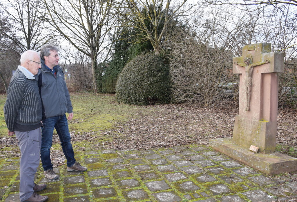 Georg und Michael Simons 2019 vis-a-vis von Adolf Meyers Grabstein für den Vater auf dem Mechernicher Friedhof. Es ist nicht mehr der originale Standort in der Nähe der Alten Kirche. Der vom „Bauhaus“-Mann aus Mechernich entworfene Stein wurde von Franz-Josef Hahn und Georg Simons durch Versetzen an den Nordrand des Kirchhofs gerettet. Foto: Kirsten Röder/pp/Agentur ProfiPress