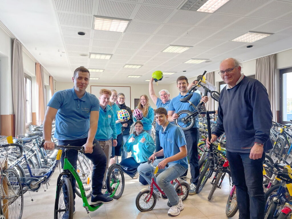 Erik Pühringer, der Leitende Pfarrer des Pastoralen Raumes St. Barbara Mechernich, mit einem Teil der von Rebekka Narres (mit erhobenem Helm) geleiteten Weltjugendtaggruppe, zu der Simon, Andreas und Daniel Schmitz, Angelina Götze, Julia und Anna Rohloff, Finn Thomasberger, Sofia Zender, Luis Kampshoff, Lauren Küppers, Noelia, Kristina Kämmerer und Lena Ingenillem gehören. Foto: Susanne Blens/pp/Agentur ProfiPress