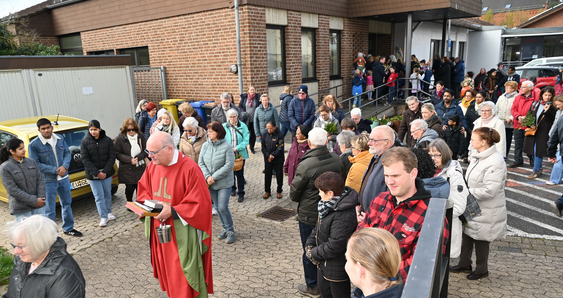 Nach dem Auftakt zum Palmsonntagsgottesdienst unter freiem Himmel formiert sich die Gemeinde zum gemeinsamen Einzug hinter Pfarrer Erik Pühringer – im Wortsinn ins Innere der Mechernicher Pfarrkirche St. Johannes Baptist, im übertragenen Sinne in eine noch unbekannte neue Kirche als „lebendige, gemeinschaftlich getragene Wirklichkeit, in der sich Menschen gegenseitig im Glauben stärken“, so der Geistliche. Foto: Manfred Lang/pp/Agentur ProfiPress