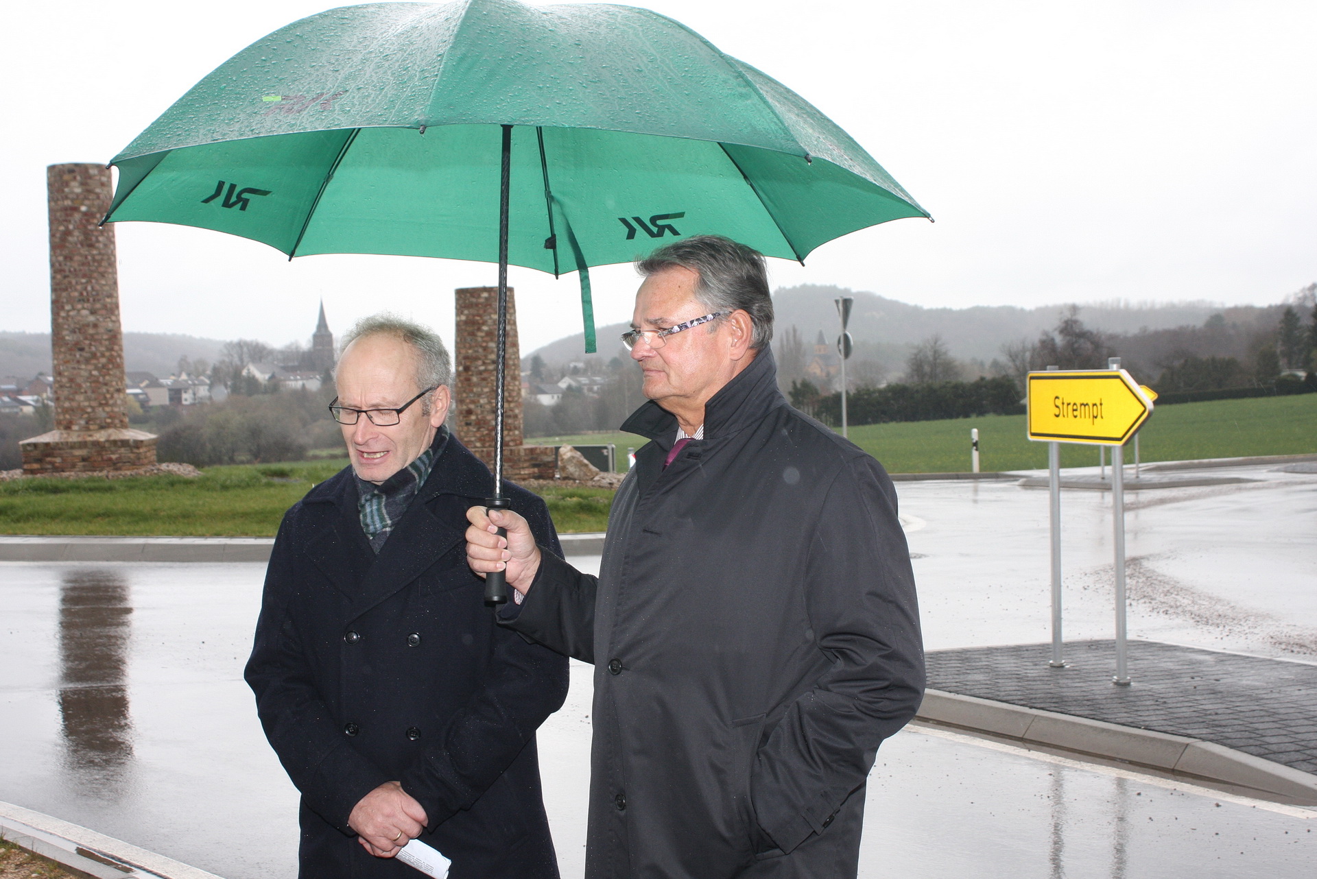 Nicht alle Erinnerungsstücke an die Mechernicher Bergbaugeschichte sind maßstabsgerecht: Einweihung des Kreisverkehrs mit Darstellungen der nach den Kreuser-Brüdern benannten Hüttenschornsteine „Kurzer Carl“ und „Langer Emil“ durch die freiwillige Renter-Arbeitskolonne „Spatenstich“. Links der damalige Mechernicher Bürgermeister Dr. Hans-Peter Schick, rechts der frühere Euskirchener Landrat Günter Rosenke. Archivfoto: pp/Agentur ProfiPress