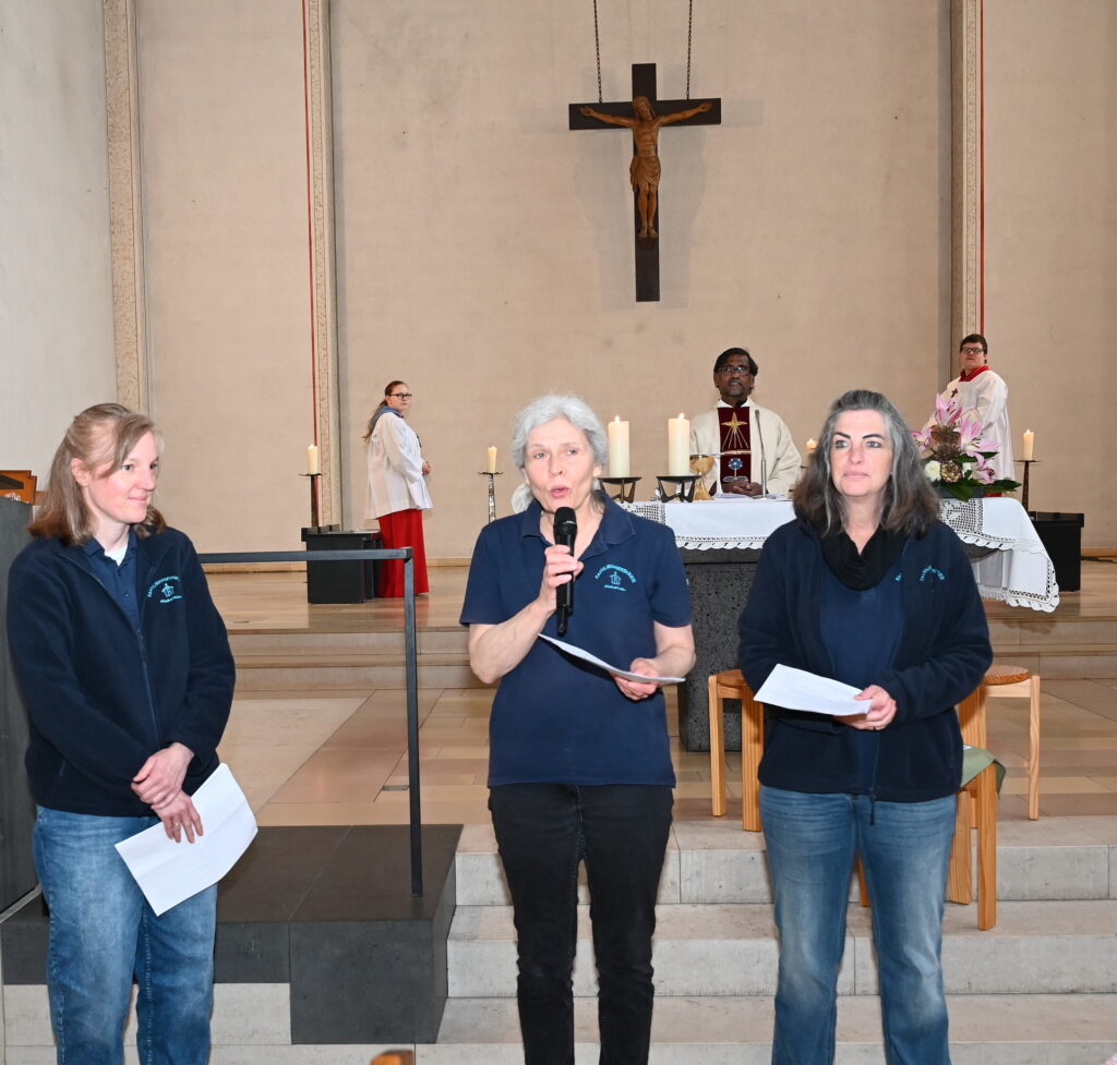 Sandra Ottersbach, Claudia Simon und Agnes Peters (v.l.) vom Familienmesskreis der Pfarre St. Johannes Baptist eröffneten den Gottesdienst zum Muttertag 2026, im Hintergrund Pfarrer George Stephen Rayappan Packiam und die Messdiener. Foto: Manfred Lang/pp/Agentur ProfiPress