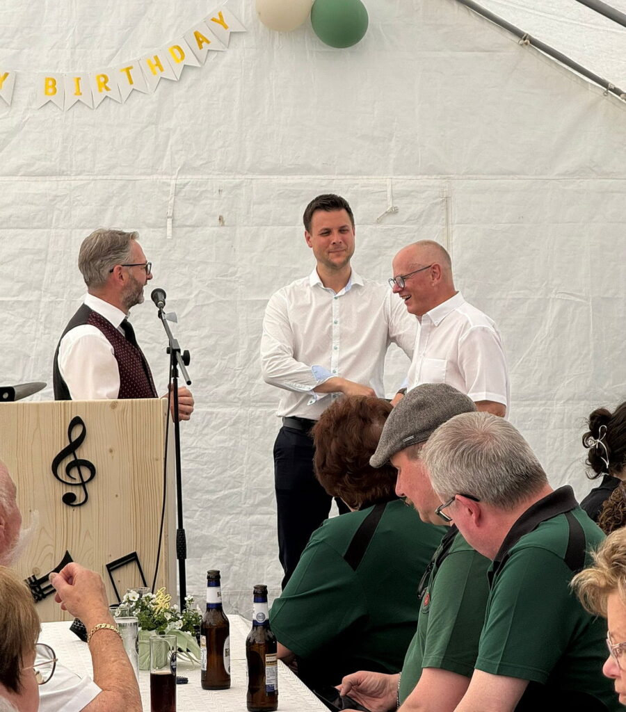 Ein besonderer Moment des Jubiläumsfestes: Bürgermeister Michael Fingel (m.) und Vize.-Landrat Ralf Claßen (r.) dankten dem scheidenden Dirigenten Stephan Hüllenkrämer für zwei Jahrzehnte musikalische Leitung. Er erhielt auch die Dirigentennadel in Gold des Volksmusikerbundes Nordrhein-Westfalen. Sein Vorgänger, Ehren-Dirigent Bernd Claßen, hatte den Verein zuvor mehr als 30 Jahre geprägt. Foto: Privat/pp/Agentur ProfiPress