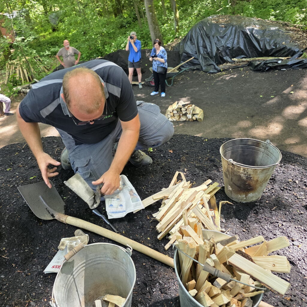 Konzentrierte Handarbeit auf dem Meiler: Markus Linden kontrolliert das Feuer im Inneren des Holzkohlenmeilers und sorgt mit Glut und „Anstochholz“ dafür, dass die Verkohlung kontrolliert in Gang kommt. Foto: Manfred Lang/pp/Agentur ProfiPress