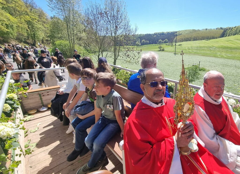 Pfarrer Dr. Shaji Thomas Manikulam aus dem indischen Kerala, der gerade bei der Communio in Christo in Mechernich für zwei Jahre hospitiert, und der Mechernicher Diakon Manfred Lang, der auch Stellvertreter des Communio-Oberen Father Jaison Thazhathil ist, segneten die am Schluss der Prozession vorüberziehenden Reiter und Fußpilger mit der Monstranz und dem Georgsreliquiar. Foto: Andrea Fingel/pp/Agentur ProfiPress