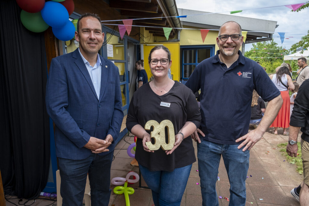 30 Jahre Kita Spatzennest Groß-Vernich II: Leiterin Jasmin Nordmann hält die Jubiläumszahl in den Händen umrahmt von Weilerswists Bürgermeister Dino Steuer (l.) und dem stellvertretenden DRK-Geschäftsführer Ralf Krutwig. Foto: Ronald Larmann/pp/Agentur ProfiPress