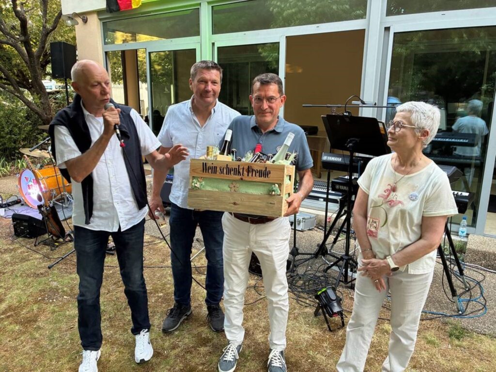 Köstliche Tröpfchen gibt es auch in Deutschland: Wilfried Hamacher und Andreas Sack übergaben Pascal Ressegaire, Vorsitzender des Comité de Jumelage und der Gastgeberin Evelyne Coupon zum Beweis diese gut gefüllte Holzkiste. Foto: Freundeskreis/pp/Agentur ProfiPress