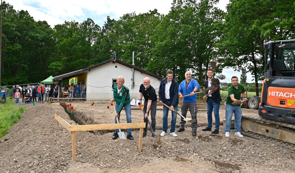 Beim symbolischen Spatenstich am neuen DGH Lessenich: (v. r.) Maurice Diefenthal (Junggesellen- und Männerverein), Bürgermeister Michael Fingel, Guido Hoffmann (Karnevalsverein), Franz Geusen (Musikverein), Michael Wolfgarten (Dorfgemeinschaft) und Klaus Weber (TuS Veytal). Bürgerinnen und Bürger verfolgten das Spektakel hinter dem Bauzaun. Foto: Henri Grüger/pp/Agentur ProfiPress