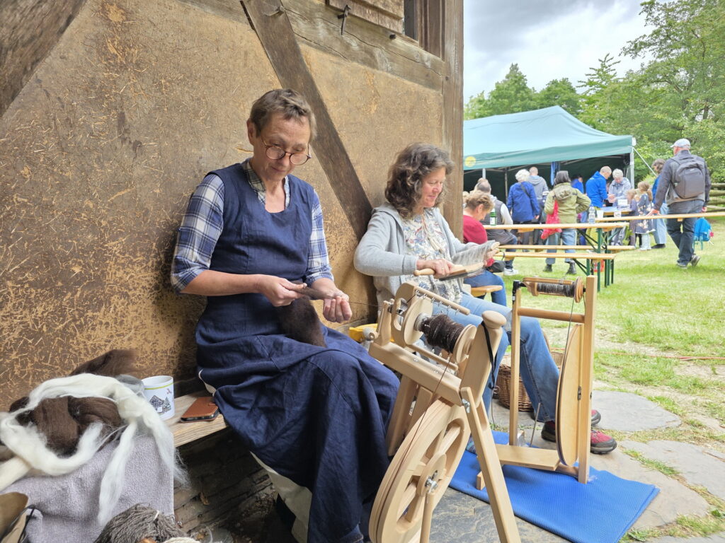 Museumshelferinnen Sonja Mauel (r.) aus Blankenheim und Bettina Elschner aus Bonn demonstrierten an Spinnrädern, wie aus Schafwolle feine Fäden entstehen. Foto: Sabine Roggendorf/pp/Agentur ProfiPress