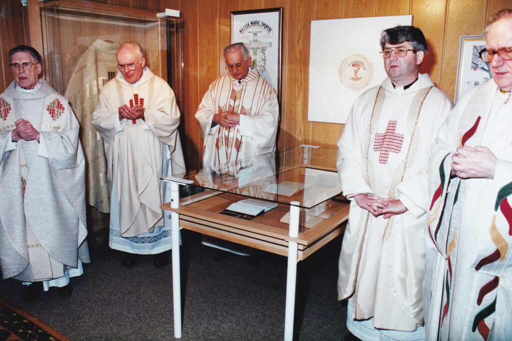Gründungsgedenktag des Ordo Communionis in Christo am 10. Dezember 1994, wenige Monate nach dem Tod der Gründerin Mutter Marie Therese: Priester, allen voran der erste Generalsuperior Karl-Heinz Haus (r.), im Gedenkzimmer der Gründerin, im Hintergrund an der Wand hängt Marti Fabers Kelch-Symbolzeichnung. Archivfoto: Marie-Thérèse Dijkstra/CIC/pp/Agentur ProfiPress