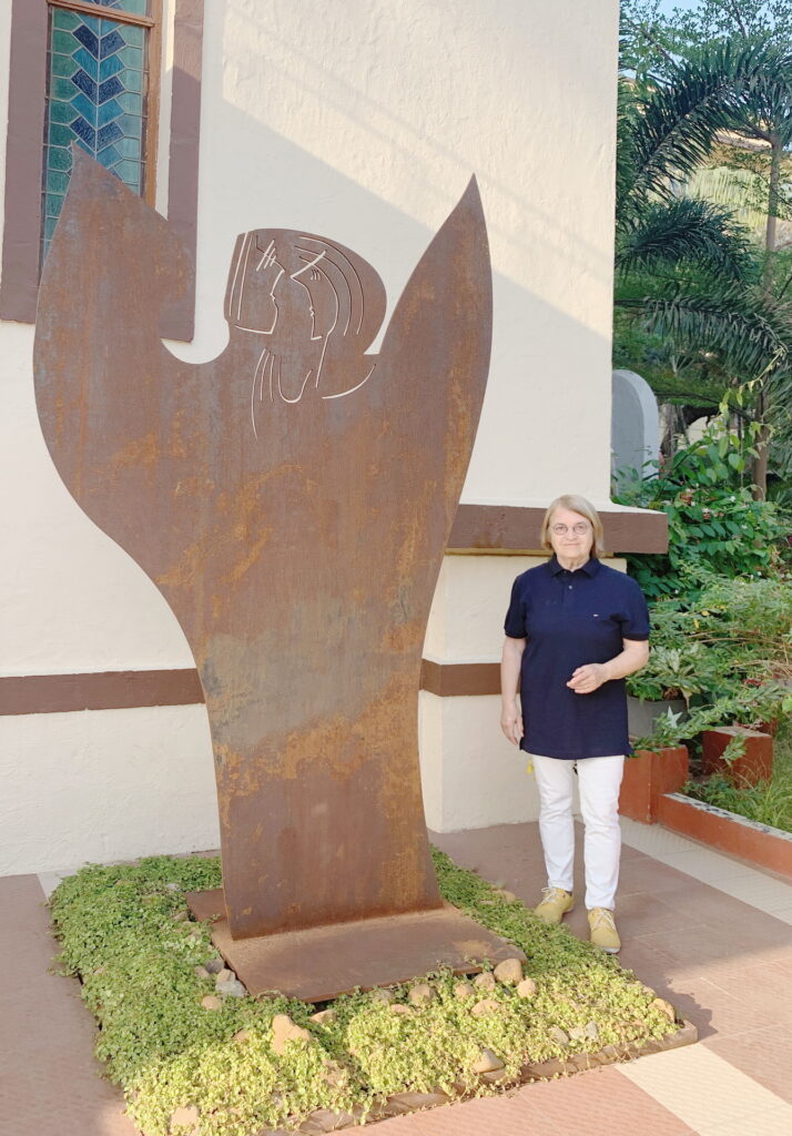 Die Zülpicher Künstlerin Marti Faber neben ihrem 2,90 Meter hohen Engel „Celestial“ vor der Franziskuskirche auf dem Mount Poinsur in Mumbai/Borivali. Die Skulptur aus Cortenstahl erinnert an 125 Jahre Missionsfranziskaner und an die Würde jedes Menschen. Foto: privat/pp/Agentur ProfiPress